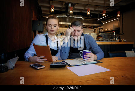 Young entrepreneurs looking over documents. At a table, in the restaurant Stock Photo