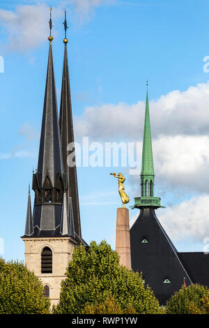 Tall church spires and a gold statue, Gelle Fra, on Monument of Remembrance; Luxembourg City, Luxembourg Stock Photo