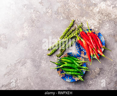 Peppers of various types of red green black in a bowl with colorful ornaments on a gray background. Flat layout. Copy space. View from above. Stock Photo