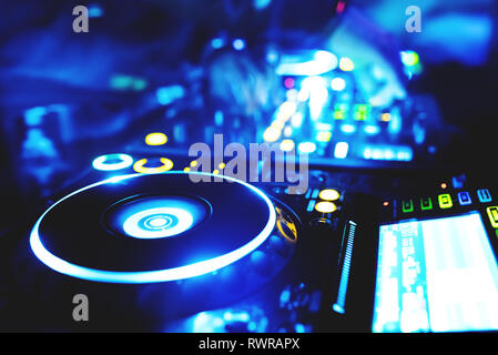 Soft view of man hand disc jockey mixing and blending music tracks on his deck in the darkness of a party or night club.Copy space for text. Stock Photo