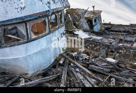 Derelict abandoned fishing boats near the harbor in Gustavus Alaska rotting in the weeds. Stock Photo