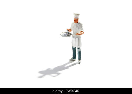 Miniature master chef in toque and apron with a pan in his hands isolated on white with copy space and shadow Stock Photo