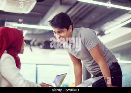 successful black muslim business woman having a meeting with her indian male colleague working on the laptop at modern startup office Stock Photo