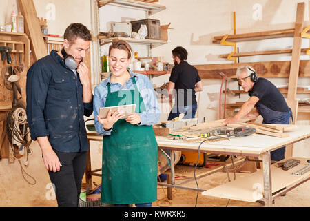Young craftsman using tablet computer online in joinery workshop Stock Photo