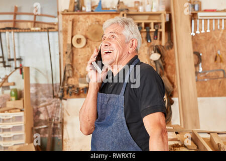 Craftsman master using the mobile phone for customer service in the carpenter workshop Stock Photo