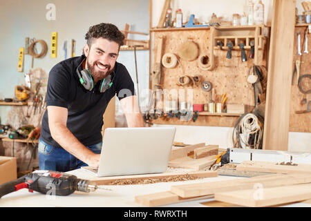 Young man as start-up founder of a craft company working on laptop computer Stock Photo