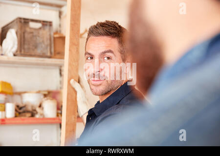 Two young workers or craftsman apprentices work together in the workshop Stock Photo