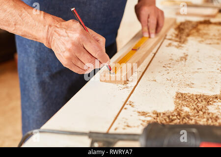 Hand of the craftsman with precise measuring with pencil and a folding rule Stock Photo