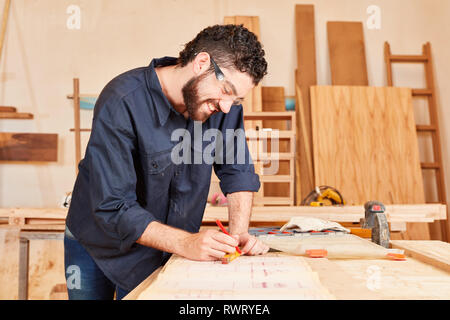 Creative young craftsman draws a construction plan in the joinery workshop Stock Photo