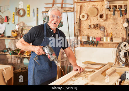 Senior as an experienced joiner master in woodworking with a drill Stock Photo