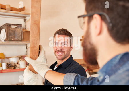 Two young craftsman apprentices or apprentices work together in the workshop Stock Photo