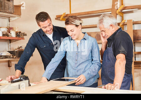 Craftsman team and wife as apprentice using tablet computer in joinery workshop Stock Photo