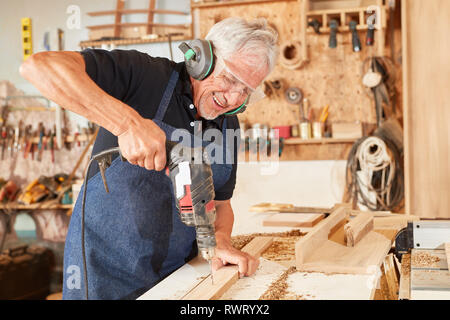 Senior as a carpenter Master works with the hand drill in the joinery Stock Photo