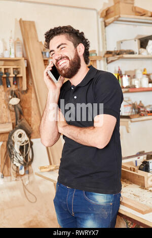 Young craftsman using mobile phone in customer service in craftsman holding Stock Photo
