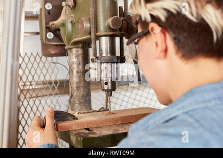 Joiner with precision drills a hole in a wood workpiece with the drill Stock Photo