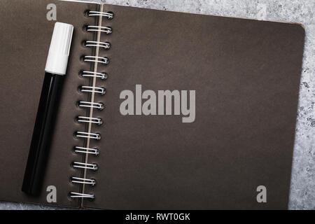 White pen and notebook for sketches with black sheets with copy space, top view Stock Photo