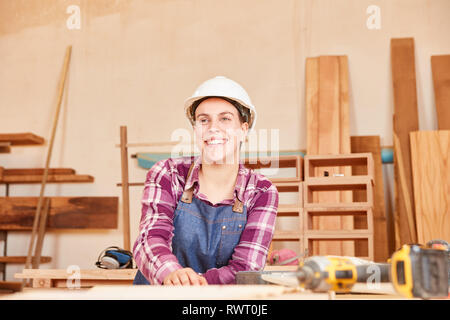 Young woman with hard hat as carpenter or joiner trainee in workshop Stock Photo
