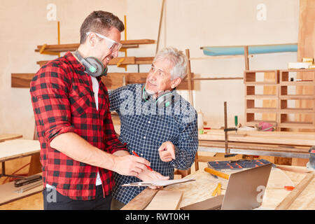 Senior craftsman and a carpenter as a team work together in the workshop Stock Photo