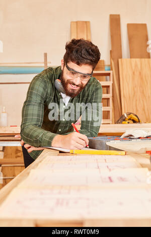 Young man as a craftsman draws a draft in the joinery workshop Stock Photo