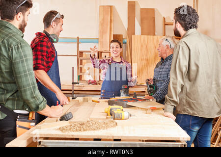 Young woman as carpenter apprentice in teaching together with colleagues in joinery Stock Photo