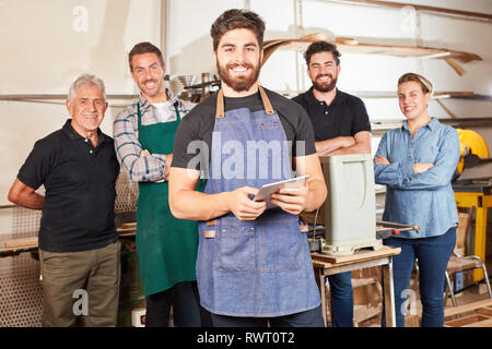 Young man as a craftsman apprentice using tablet computer in his joiner's shop Stock Photo