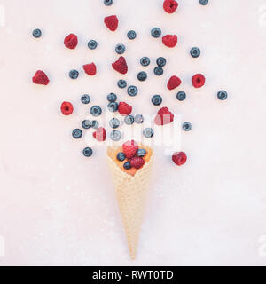 Creative Summer concept composition flat lay top view sweet fresh red raspberries blueberries ice cream waffle cone pink background copy space Templat Stock Photo