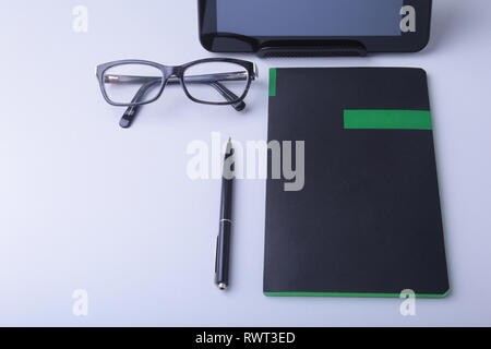 Business concept. Top view of kraft spiral notebook, glasses, smartphone and black pen isolated on background for mockup. Stock Photo