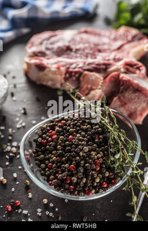 Seasoning four kinds of pepper peas in bowl with raw meat and herbs. Stock Photo