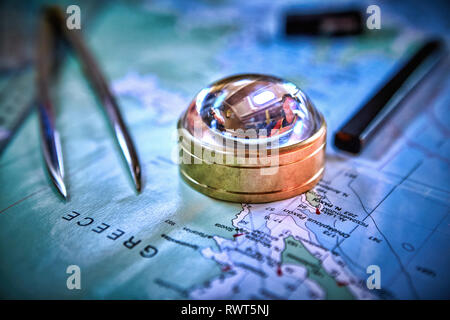 Magnetic compass and magnifying glass on map Stock Photo