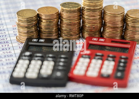 coins stacks with red and black Calculators in front Stock Photo