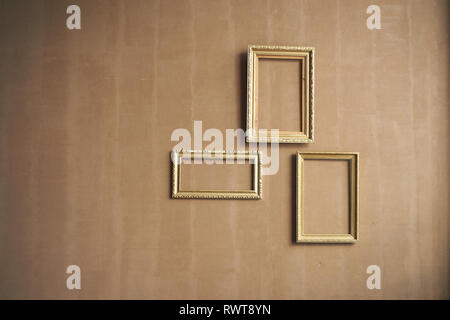 Minimalism.Brown wall with empty gold frames. Stock Photo