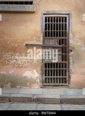 Closed rusted iron bars cell door and weathered grunge stone wall in closed abandoned prison at Cairo Citadel, Egypt Stock Photo