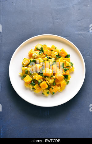 Stir-fried pumpkin with eggs on plate over blue stone background. Pumpkin and egg stir fry in thai style. Top view, flat lay Stock Photo