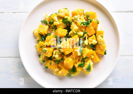Close up of stir-fried pumpkin with eggs on plate over white wooden background. Pumpkin and egg stir fry in thai style. Top view, flat lay Stock Photo
