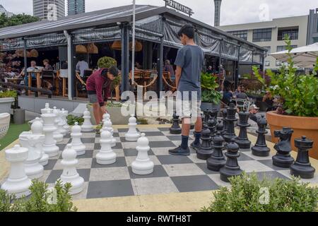 Tue Jan 1st 2019,Auckland New Zealand - Two teenage boys play a game of chess on a big outdoor chessboard with large chess pieces. Stock Photo