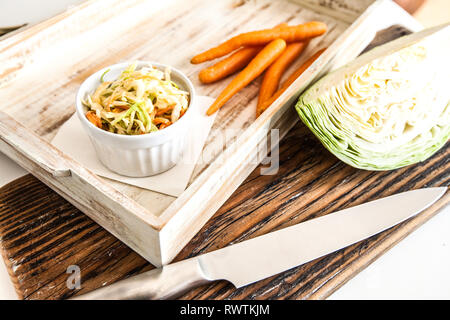 Side view of bowl filled with coleslaw isolated on wood background Stock Photo