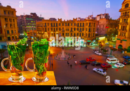 Enjoy the glass of mint tea with cinamon, watching the sunset over the busy Talaat Harb square, full of cars and lined with stores and tourist cafes,  Stock Photo