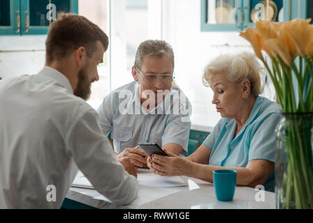 Senior couple talking with advisor, planning to sell a property and to invest money. Consulting service concept. Stock Photo