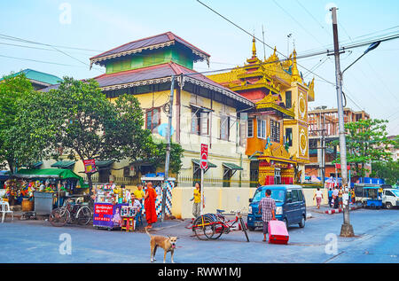 YANGON, MYANMAR - FEBRUARY 15, 2018: The building of Buddhist Damikar Yarma monastery with scenic golden pyatthat roof and numerous food stalls around Stock Photo