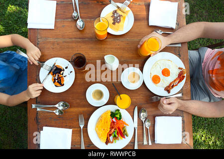 Continental breakfast of the family with pancakes, eggs, bacon, orange jiuce and coffee. Top view Stock Photo