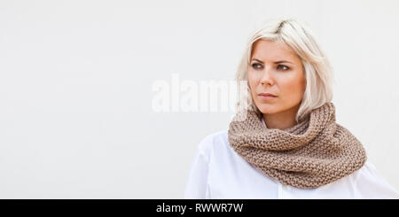 Pretty young woman in warm beige wool knitted snood scarf. Stock Photo