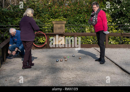 Three people playing a game of Petanque outdoors in Harrogate, North Yorkshire, England, UK. Stock Photo