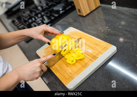 Happy young woman cutting fresh vegetables in kitchen Stock Photo