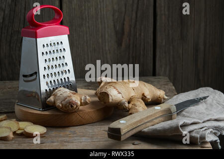 Ginger root and grater on kitchen table. Stock Photo