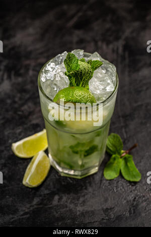 Refreshing mint cocktail mojito with rum and lime, cold drink or beverage with ice on black background Stock Photo