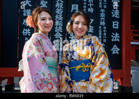 Women wearing kimono, the national tradition costume of Japan, walking on Nakamise dori, a street with food and souvenirs shops. Senso-ji Buddhist Tem Stock Photo