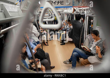 Japanese people inside underground metro train, Asian commuters traveling during rush hour, tourists on subway train. Tokyo, Japan, Asia Stock Photo