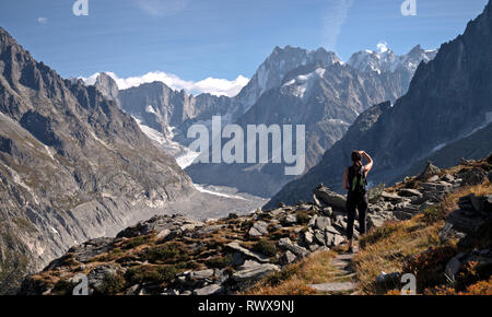 A lone female Hiker looks out over a  glacier valley in the region of Chamonix in the alps of France. Stock Photo