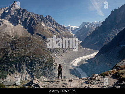 A lone female Hiker looks out over a  glacier valley in the region of Chamonix in the alps of France. Stock Photo