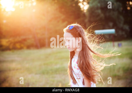 Beautiful Teen Girl is enjoying nature in the park at Summer sunset Stock Photo